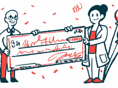 Two people each hold one side of a giant check, flanked by balloons and amid confetti.