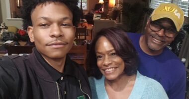 A young man takes a selfie with his parents.