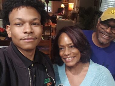 A young man takes a selfie with his parents.