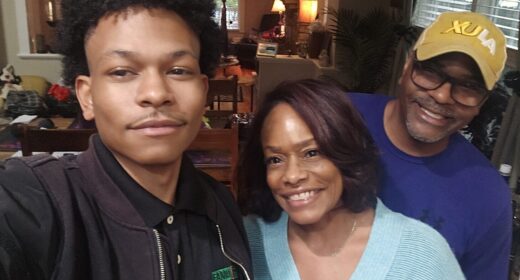 A young man takes a selfie with his parents.