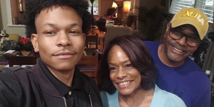 A young man takes a selfie with his parents.