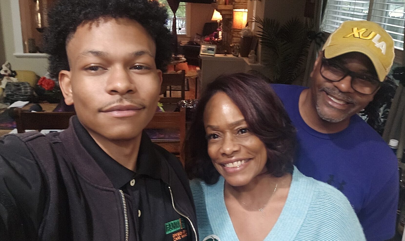 A young man takes a selfie with his parents.