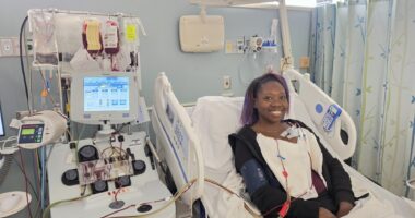 A woman lies in a hospital bed while receiving a blood exchange transfusion to treat her sickle cell disease.
