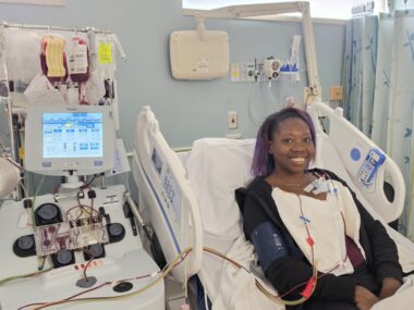 A woman lies in a hospital bed while receiving a blood exchange transfusion to treat her sickle cell disease.