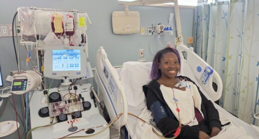 A woman lies in a hospital bed while receiving a blood exchange transfusion to treat her sickle cell disease.