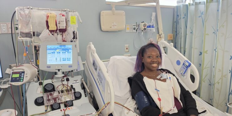 A woman lies in a hospital bed while receiving a blood exchange transfusion to treat her sickle cell disease.