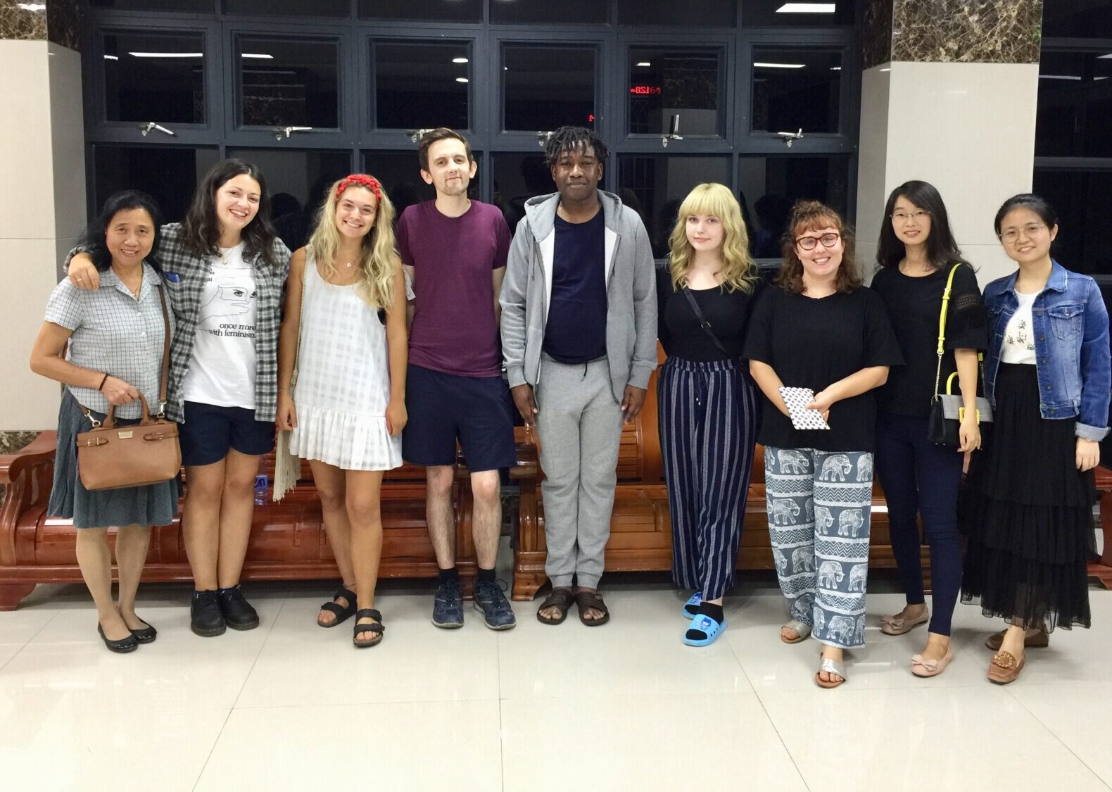 Nine adults, a mix of teachers and students, stand side by side and pose for a photo.